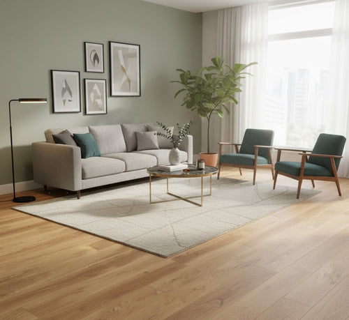 Helles Wohnzimmer mit großen Fenstern, Eiche-Massivholzdielen, grauem Sofa, zwei grünen Sesseln, Teppich und modernem Couchtisch vor pastellgrüner Wand.