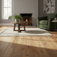 Rustikale Kiefer-Massivholzdielen in B-Sortierung; deutlich sichtbare Äste, Risse und Maserungen verleihen dem Boden eine natürliche, warme und authentische Optik.