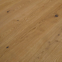 Rustikales Eiche-Parkett mit lebendiger Maserung, natürlichen Ästen und schwarz gespachtelten Rissen in warmem Holzfarbton.