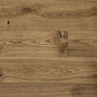 Rustikales Eiche-Parkett mit lebendiger Maserung, natürlichen Ästen und schwarz gespachtelten Rissen in warmem Holzfarbton.