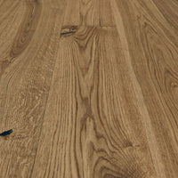 Rustikales Eiche-Parkett mit lebendiger Maserung, natürlichen Ästen und schwarz gespachtelten Rissen in warmem Holzfarbton.