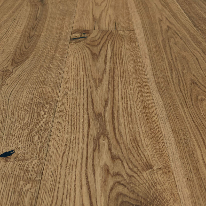 Rustikales Eiche-Parkett mit lebendiger Maserung, natürlichen Ästen und schwarz gespachtelten Rissen in warmem Holzfarbton.