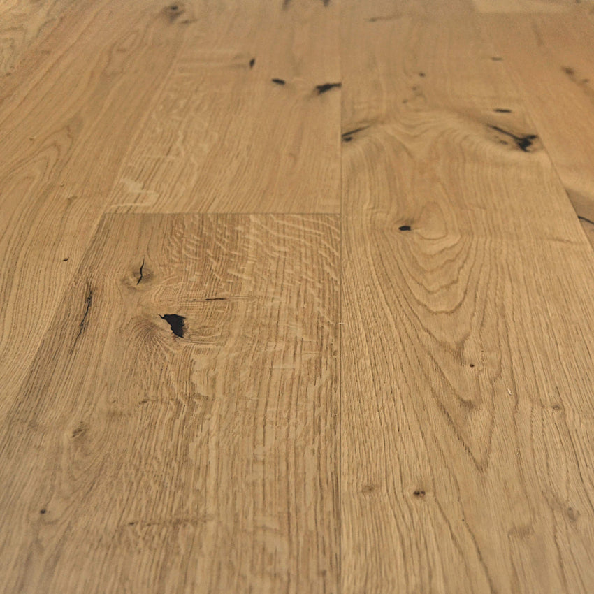 Rustikales Eiche-Parkett mit lebendiger Maserung, natürlichen Ästen und schwarz gespachtelten Rissen in warmem Holzfarbton.