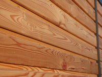 Detailaufnahme der horizontalen Rhombusschalung aus Lärchenholz mit sichtbarer Maserung und warmem Naturfarbton an einem modernen Gartenhaus