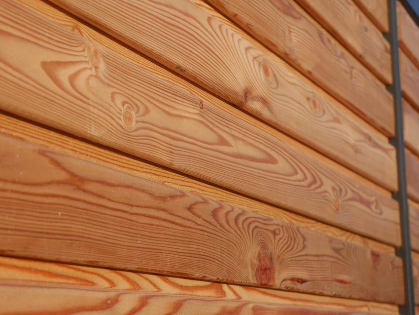 Detailaufnahme der horizontalen Rhombusschalung aus Lärchenholz mit sichtbarer Maserung und warmem Naturfarbton an einem modernen Gartenhaus