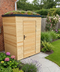 Moderner Gartenschrank aus Lärchenholz mit Gründach und Rhombusfassadenprofil, eingebettet in einen gepflegten Garten mit Blumen und Rasen.