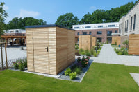 Mehrere moderne Gartenschränke aus Lärchenholz mit Rhombusfassadenprofil in einer gepflegten Wohnanlage mit Grünflächen und Blumenbeeten.