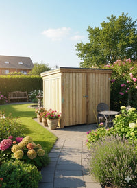 Holzgerätehaus im gepflegten Garten, umgeben von blühenden Blumen, Terrasse und Wegen