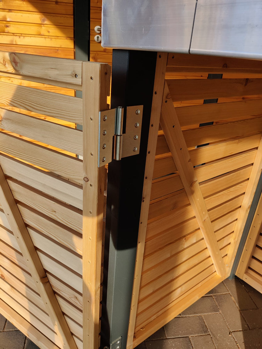 Detailansicht der Mülltonnenbox KLARE LINIE mit geöffnetem Türflügel, stabilen Edelstahlscharnieren und Holz-Rhombusverkleidung.